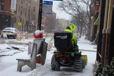  A snow removal workers clears a Damen Avenue sidewalk.  