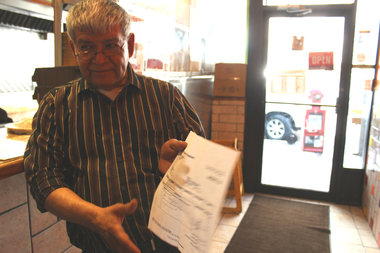  Guerzo Bautista, owner of Angela's Burrito Style, 2556 N. Clark St., holds up a bill. He said it cost $900 to repair the broken door and cash register after the early Thursday burglary.  