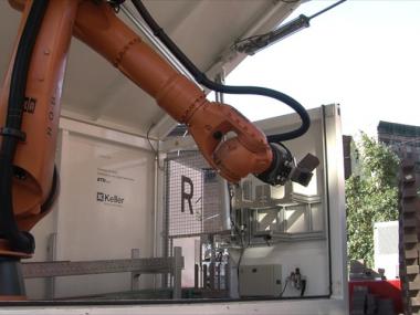 An industrial robotic arm, mounted on a mobile trailer, was shipped from Switzerland to New York City to construct the 