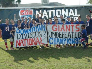 The Downtown Giants hold up a homemade championship banner after pulling off a 20-13 victory in overtime in the championship game against Rhode Island's Central Falls Panthers in Orlando, Fla.