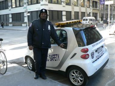 NYU campus security officer Collin Campbell stands in front of the new patrol vehicle, a Smart car.