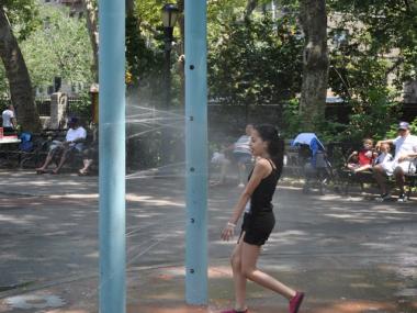 Alexa Colon, 9, cools off in the sprinklers at J. Hood Wright Park in Washington Heights, Tuesday.