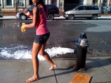 A young girl cools off in the spray of a fire hydrant.