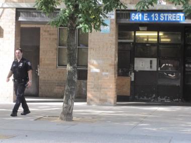 A police officer surveys the scene outside the apartment complex on 13th Street where a food delivery man was robbed Friday afternoon.