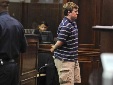 Michael Enright, 21, in handcuffs at his arraignment.