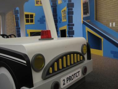 The Junior Officers Discovery Zone includes a stationary police car and a 1st Precinct station house.